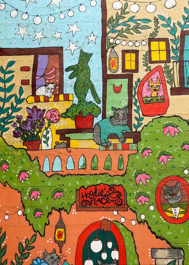 Colorful mural featuring drawings of cats, bushes and windows